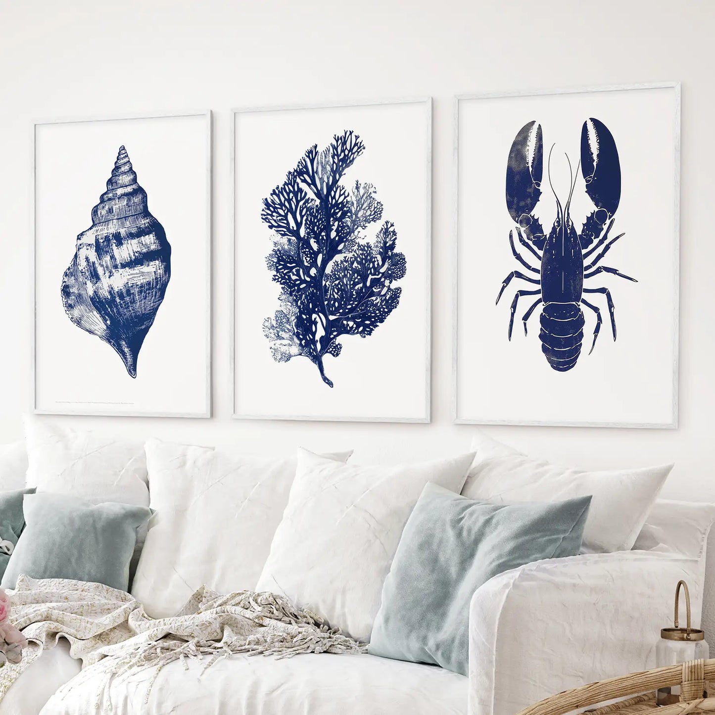 Nautical themed wall art prints of a shell, coral, and lobster. Minimal marine art. White frames for apartment.