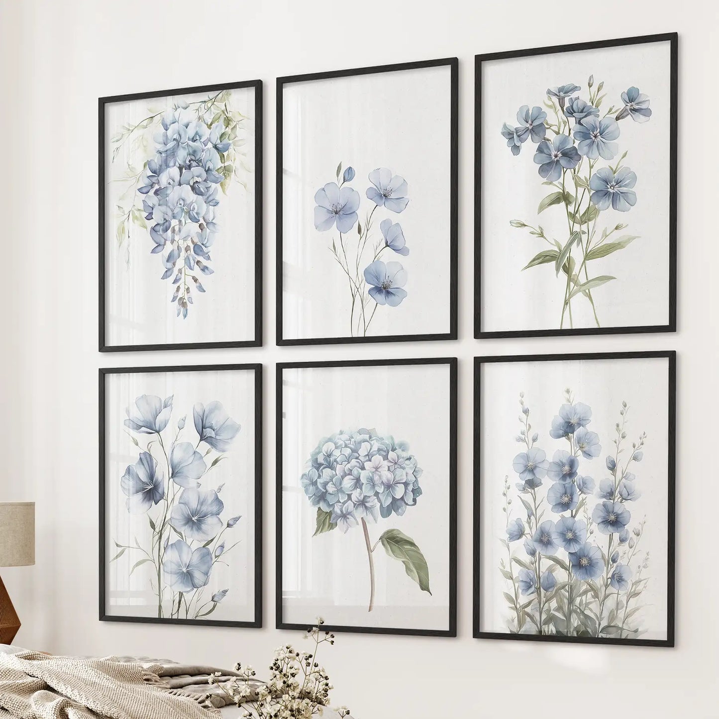 Blue watercolor floral wall art set of 6 prints featuring hydrangeas, wildflowers, and leaves. Black frames over the bed.