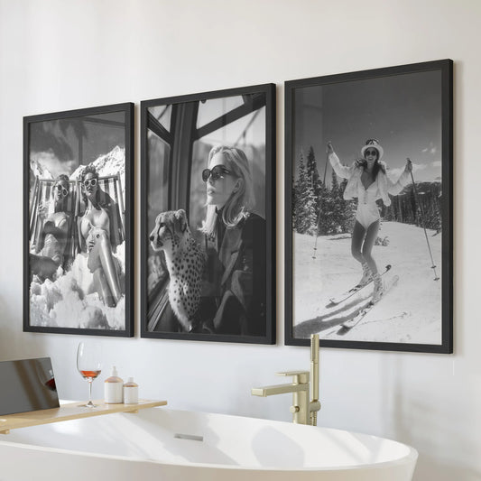 A three-piece wall art set of vintage alpine skiing scenes in black frames hangs above the bathtub, giving the bathroom a crisp lodge touch.
