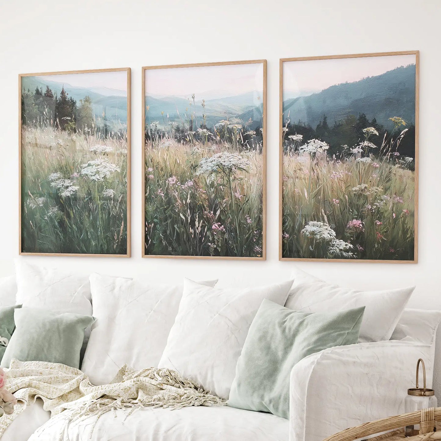 Set of 3 landscape wall art prints featuring a wildflower meadow with soft green and pastel tones. Thinwood frames above the sofa.