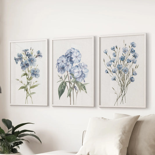 Neutral botanical florals, a set of three wall prints in white frames, span the wall over the sectional sofa to balance the family room.