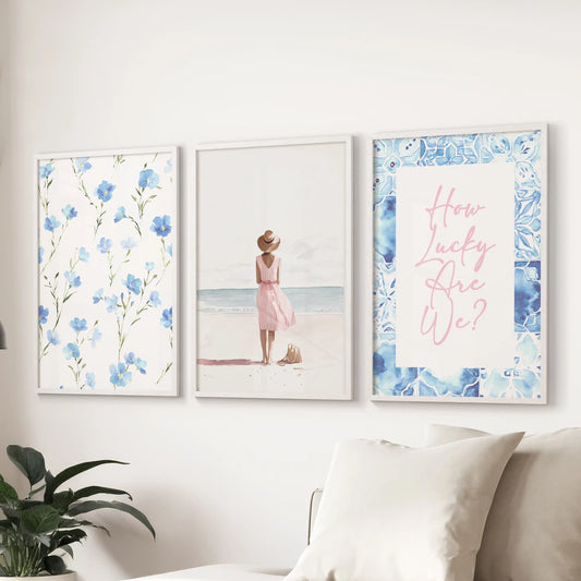 Three white-framed wall prints with the 'How Lucky Are We' quote hang over the sofa, filling the sitting room with soft blue and optimistic charm.