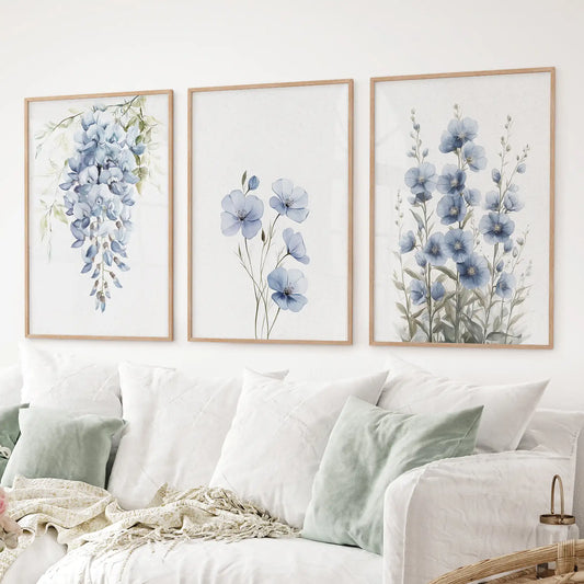 Watercolor floral wall art prints featuring wisteria, delicate blooms, and tall blue flowers. Thinwood frames above the sofa.