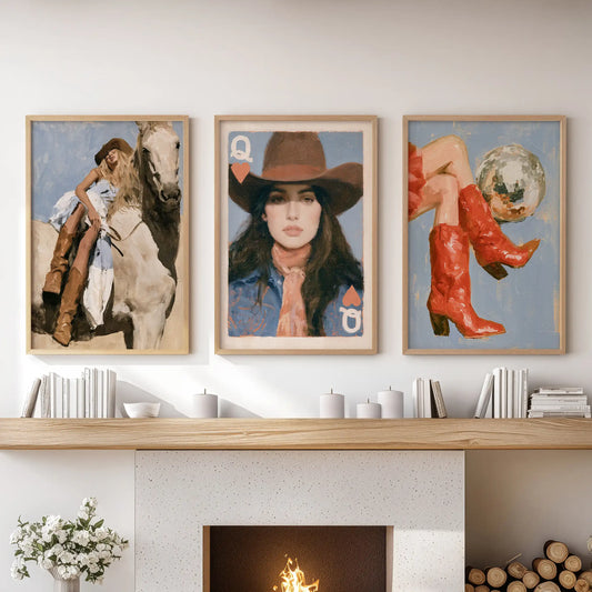 Three wall art prints of red cowgirl boots are set in natural oak frames over the living room fireplace, anchoring the space with bold western flair.