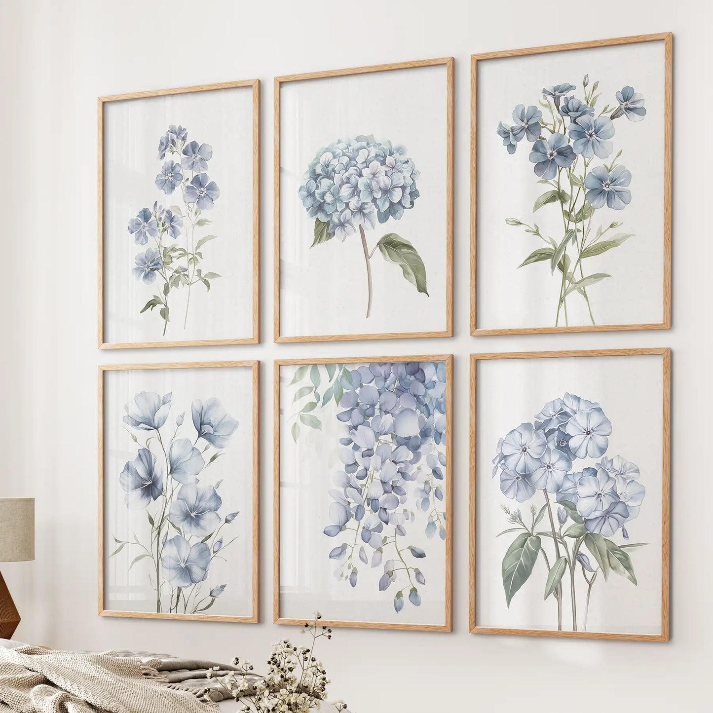 Botanical wall art set with watercolor blue flowers like hydrangeas and wisteria. Thinwood frames over the bed.