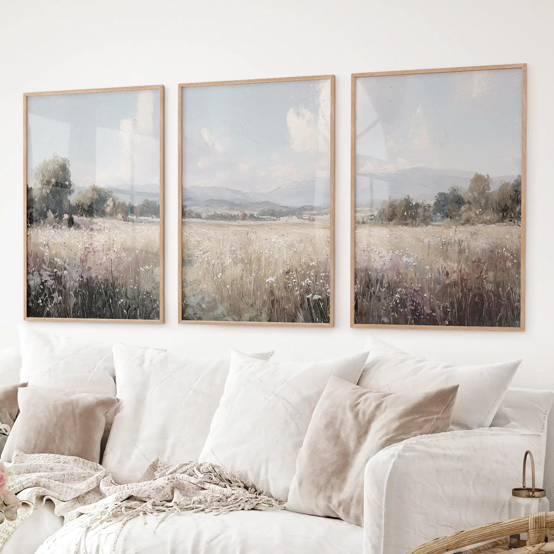 Set of three countryside landscape prints featuring a wildflower field and distant hills in neutral colors. Thinwood frames over the couch.