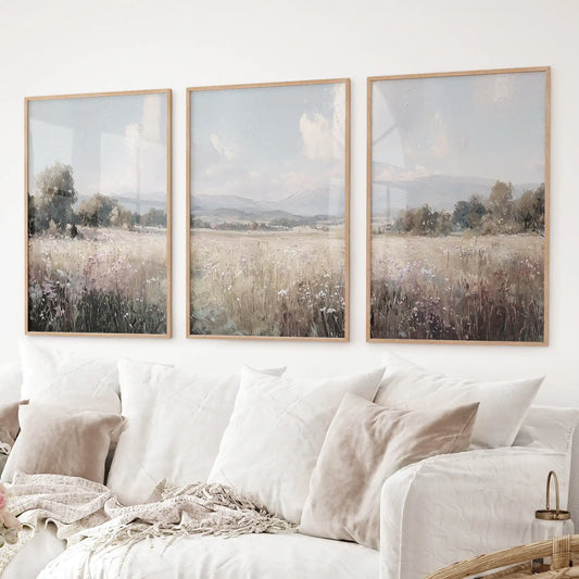 Set of three countryside landscape prints featuring a wildflower field and distant hills in neutral colors. Thinwood frames over the couch.