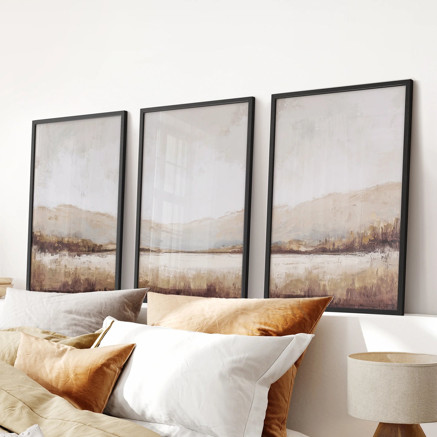 Neutral beige landscape wall art set of three in black frames hangs over a bed, bringing soft, minimalist texture to a calm bedroom.