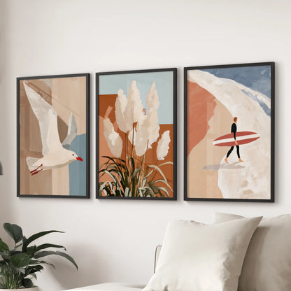 Three black-framed beach art prints in terracotta tones span the wall above the sectional, warming the family room with relaxed modern coastal ease.