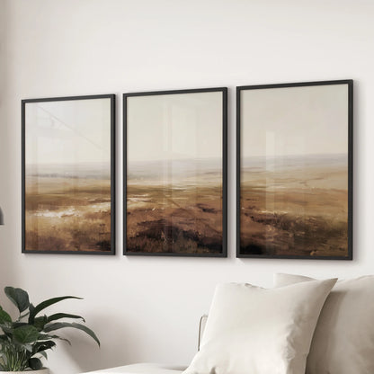 Autumn countryside wall art set of 3 in muted neutrals, black framed and arranged over a sectional to warm a modern living room.