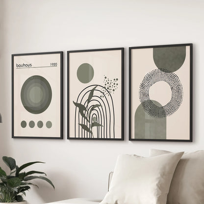 Bauhaus-inspired prints, three-piece set in black frames, anchor lounge walls above a sectional sofa with crisp, graphic sage-green forms.