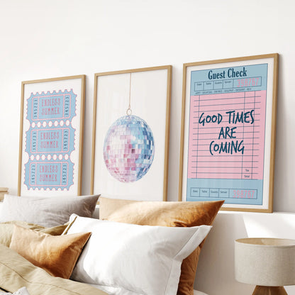 Mounted above the headboard, three oak-framed prints blend guest check, disco ball, and beach ticket elements for a cool, preppy blue bedroom vibe.