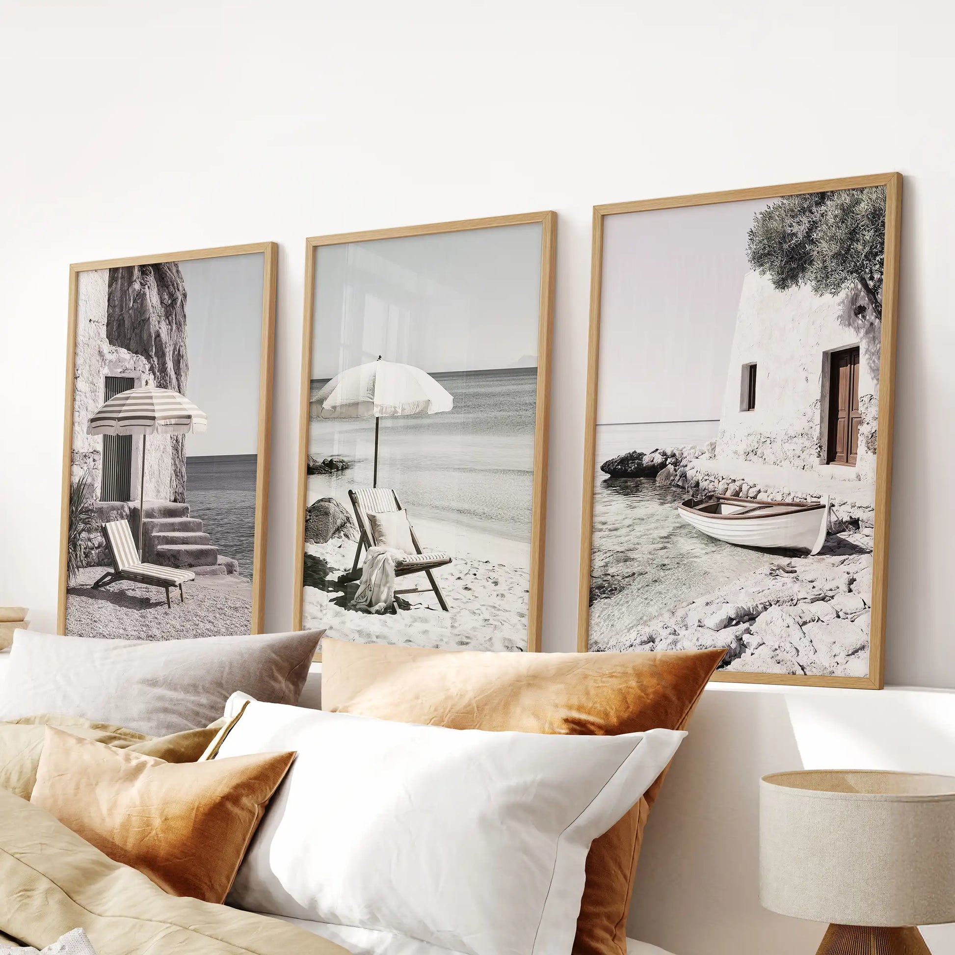 Beach umbrellas on a Greek shore, a set of three framed wall prints in light oak, placed above the bed to warm the bedroom with gentle seaside charm.
