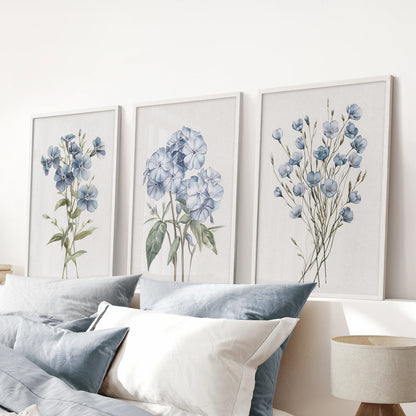 Neutral botanical  watercolor flowers, a set of three wall art prints in white frames, line the space over the bed headboard in the bedroom.