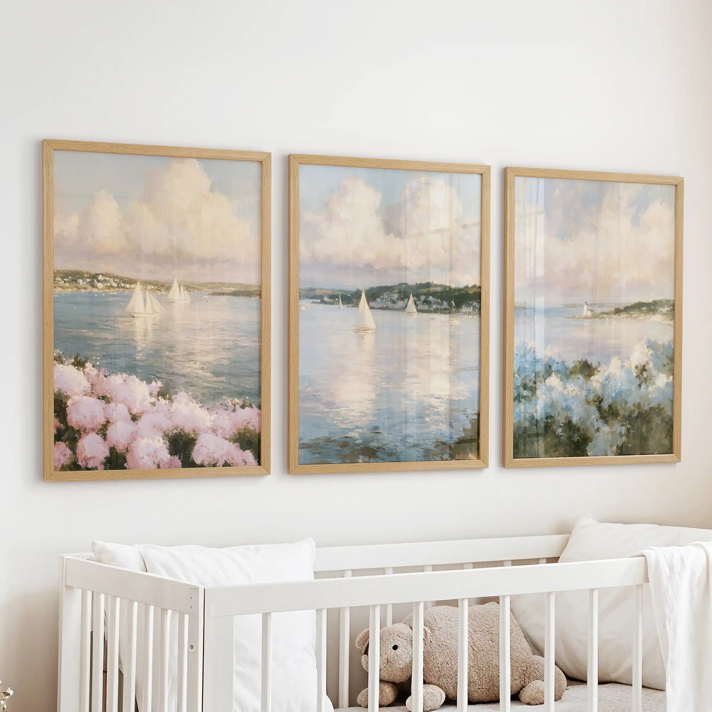 Framed wall prints in a set of three feature hydrangea beach flowers above the infant room cot. Natural wood frames complement pink and blue seaside blooms.