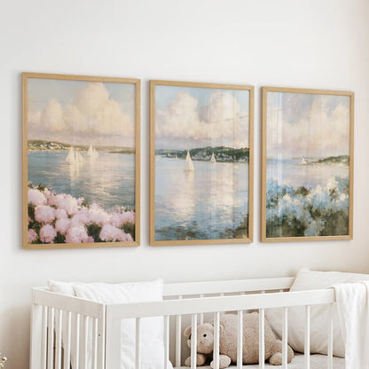 Framed wall prints in a set of three feature hydrangea beach flowers above the infant room cot. Natural wood frames complement pink and blue seaside blooms.