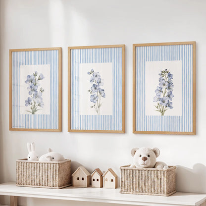 Blue watercolor wildflowers 3-print wall set in natural wood frames, arranged over a toy organizer in a children's room.