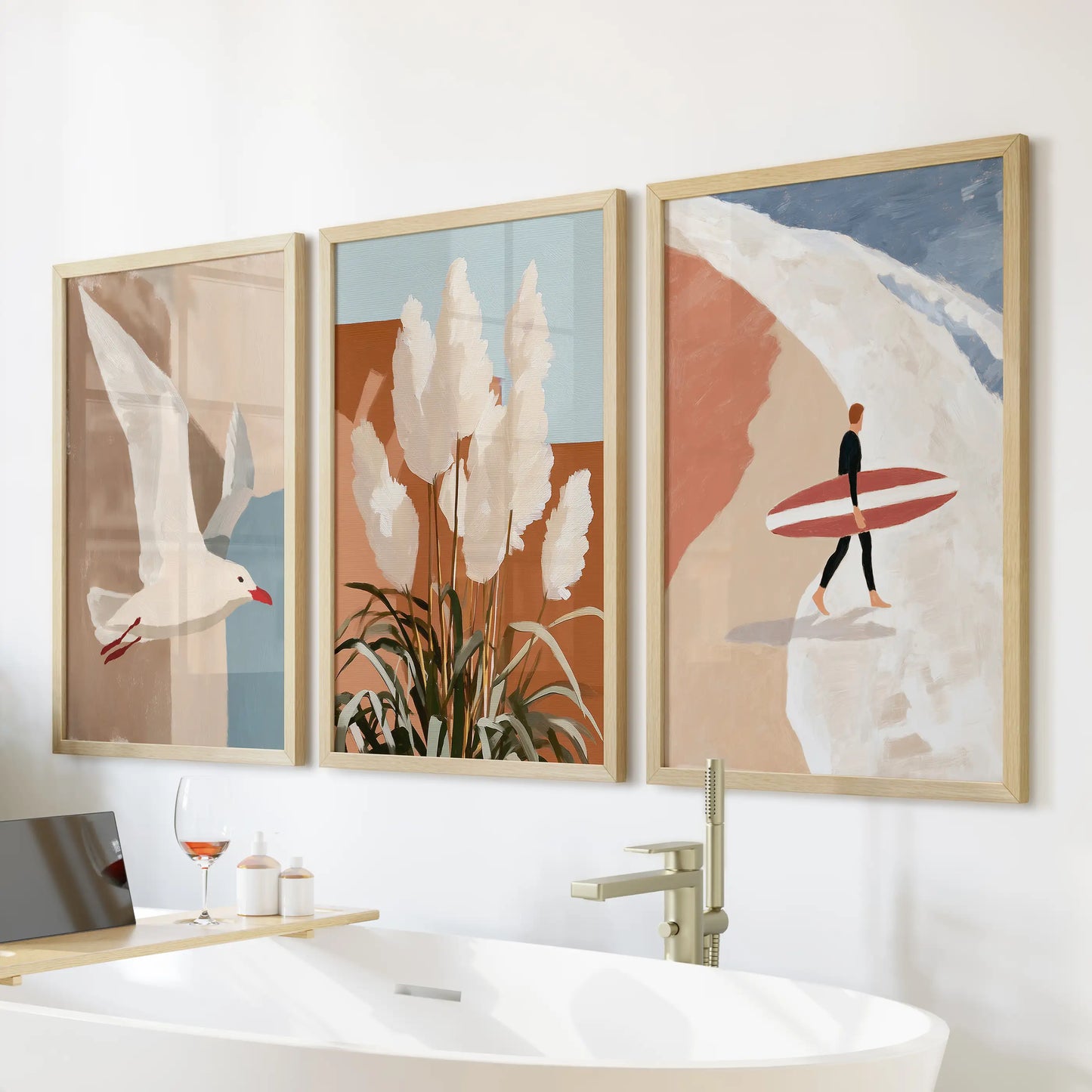 Warm wood frames hold three terracotta-toned coastal prints over the bath, creating a cozy, spa-like mood with gentle beachside charm.