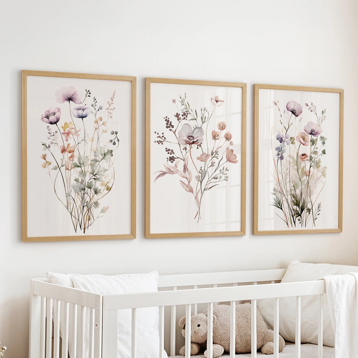 Three-piece oak-framed botanical wall art displayed over the crib, adding a gentle natural tone to the baby room.