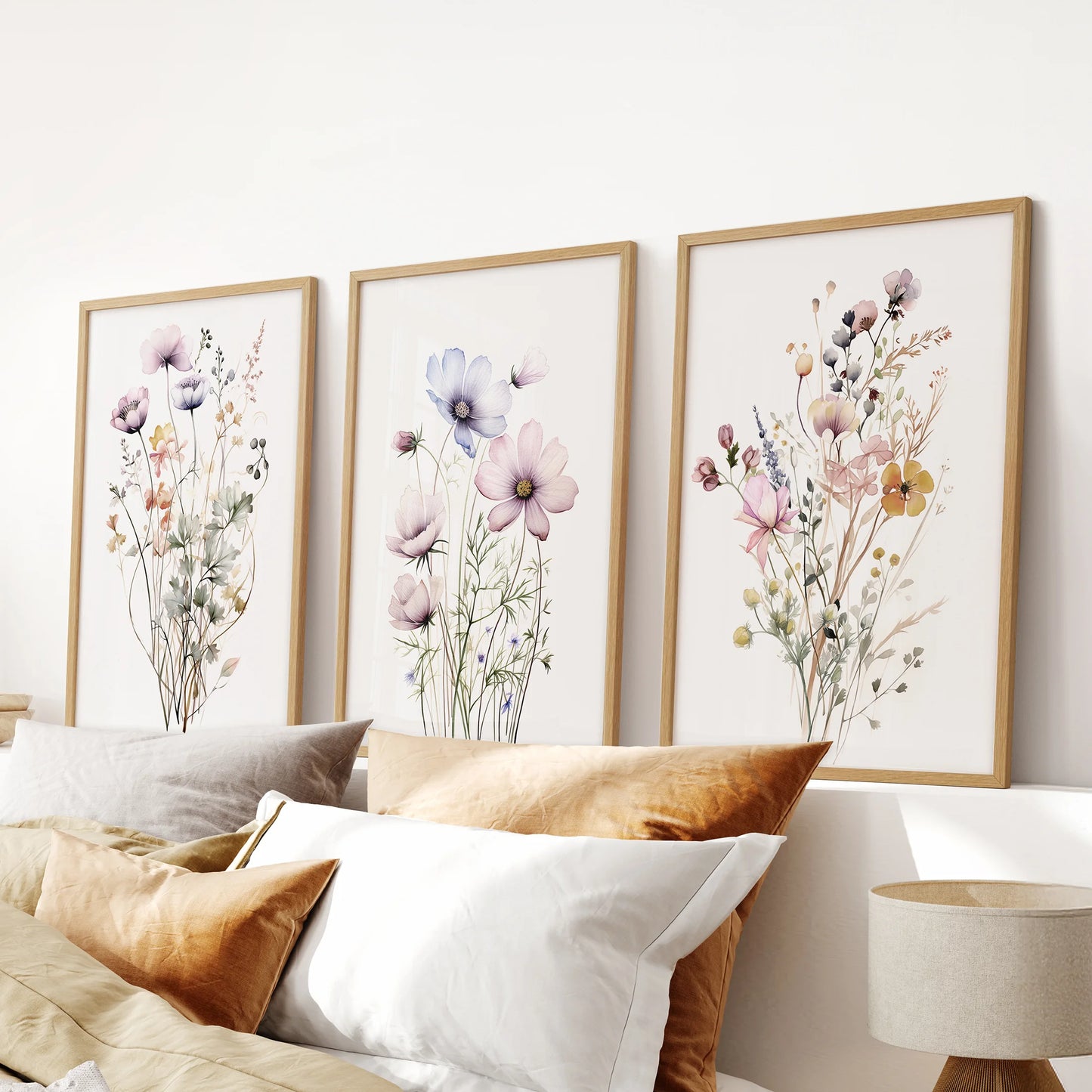 Cottagecore floral prints, a three-piece wall art, are framed in warm wood and centered over the bed's headboard to ground the bedroom with greenery.
