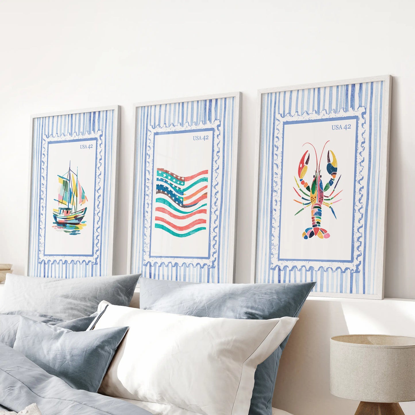 A 3-piece suite of bright coastal wall scenes in slim white frames floats above the headboard, freshening a tranquil blue bedroom.