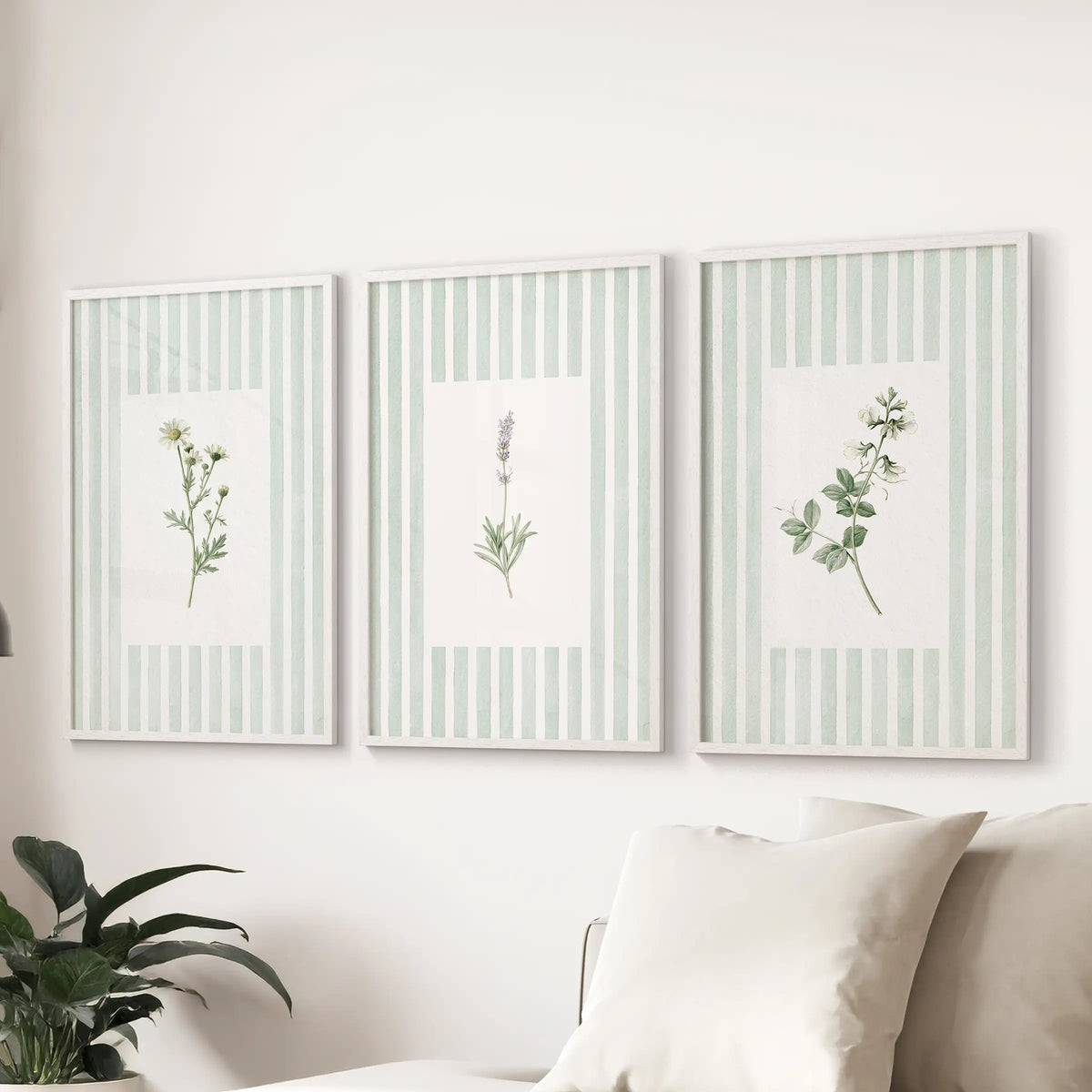 Sage botanical floral wall art in a set of three white framed prints is displayed above a couch in the living room.