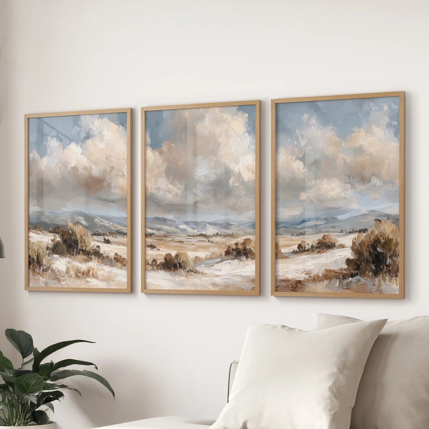 Moody vintage landscapes, a 3-poster bundle in solid oak frames, elevate the living room with coastal-and-country calm, spanning the wall above the sectional.