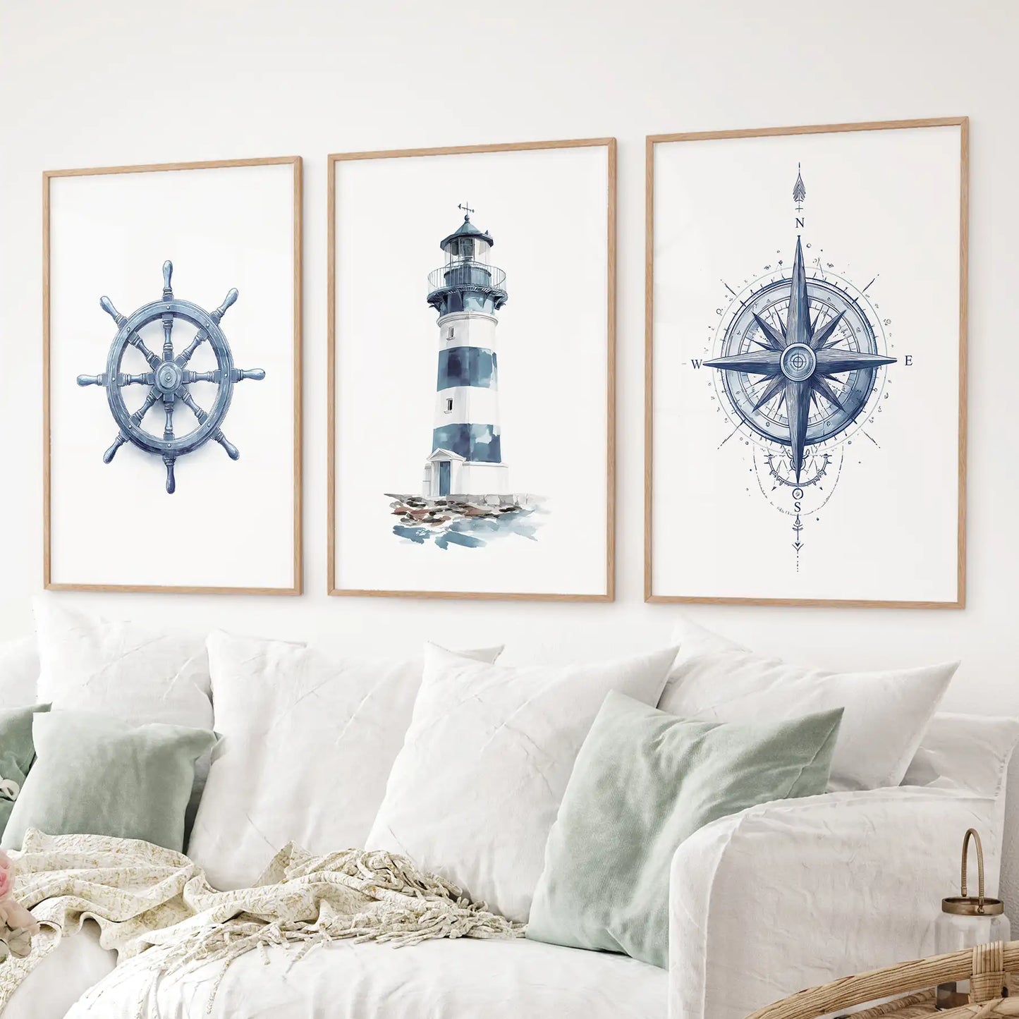 Nautical art set watercolor lighthouse, compass rose, and ship helm prints. Thinwood frames over the couch.