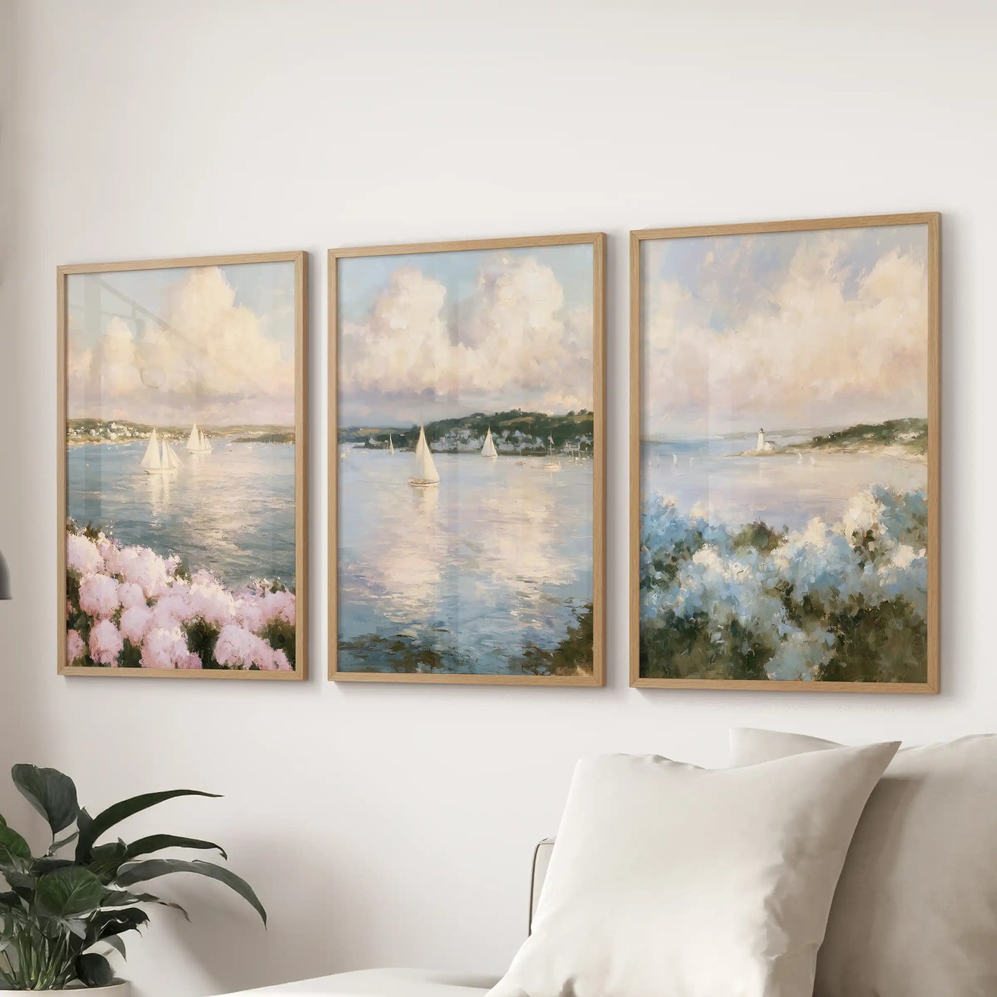 A three-piece wall art set featuring Nantucket sailboats hangs above the living room sofa. Wooden frames present a breezy coastal trio of masts and glittering tide.