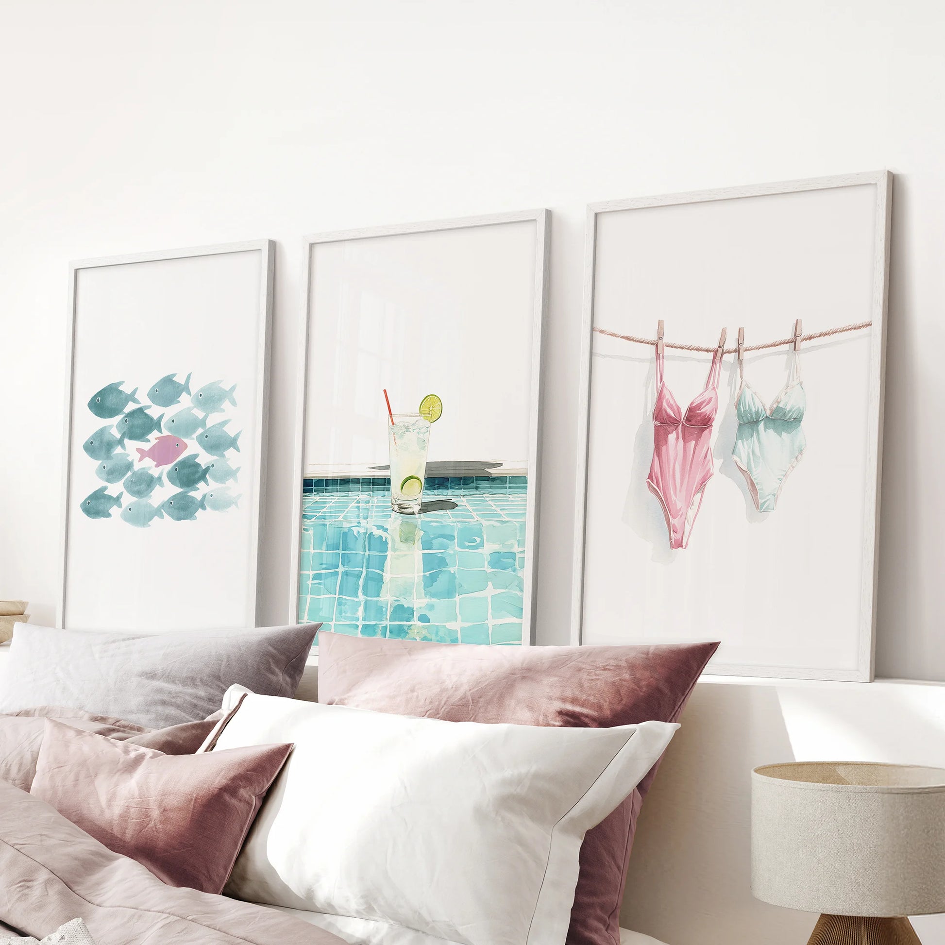 Three playful cocktail prints in white frames brighten a pink bedroom, their fizzy hues floating over the bed like a burst of summer color.