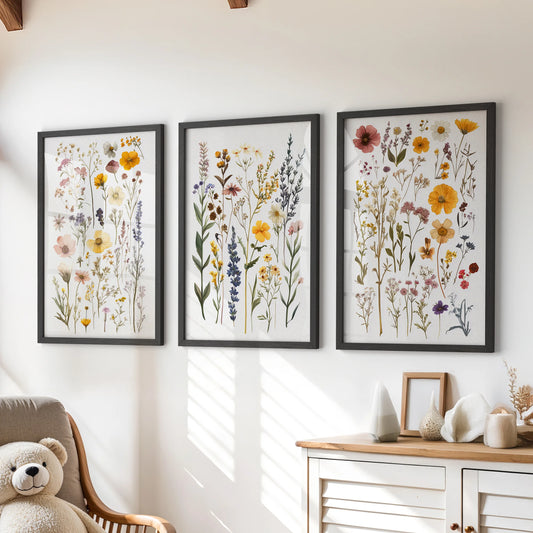 A wall art set of 3 wildflower bouquet prints in sleek black frames brightens a children's room, styled just above the dresser.