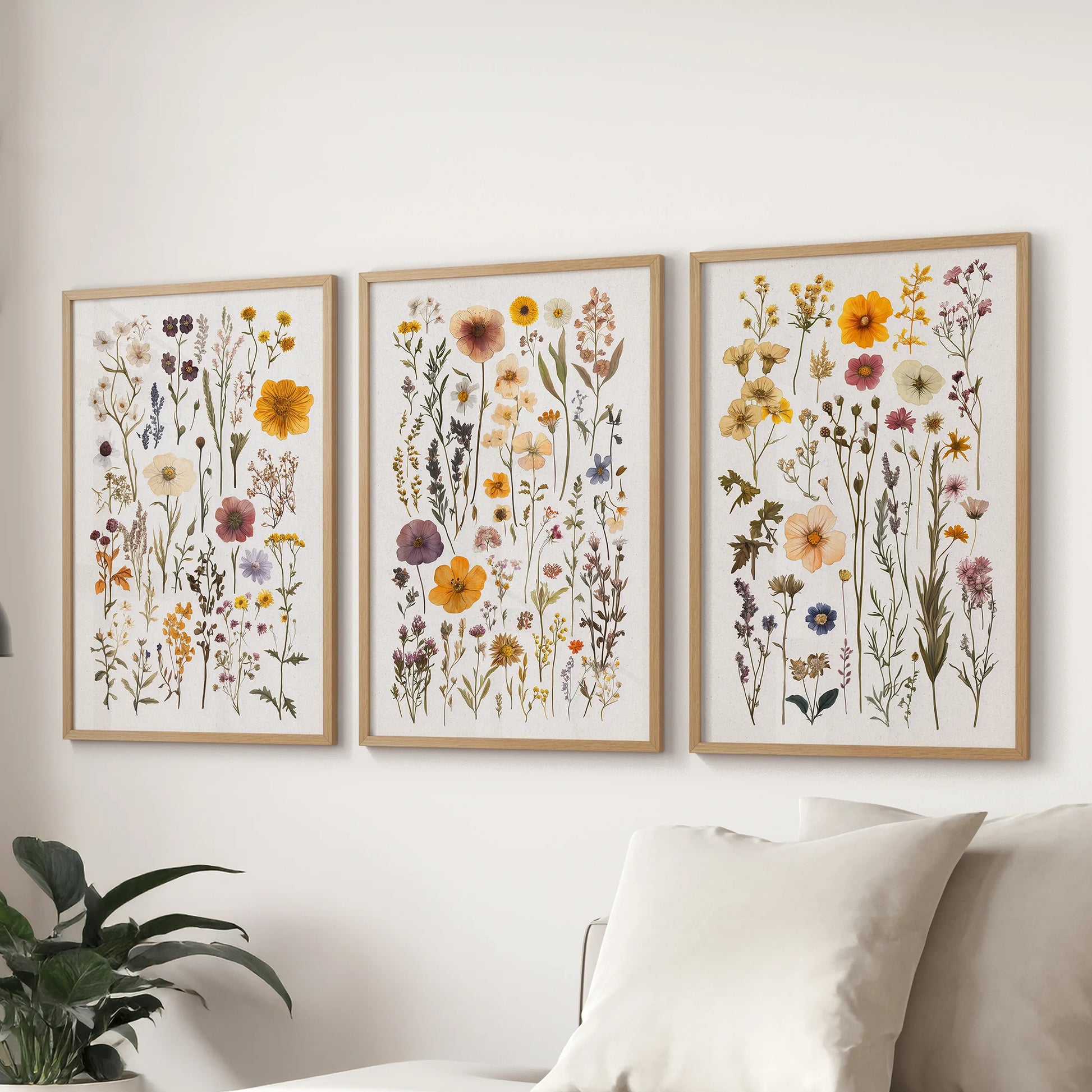 Botanical flower illustrations, a 3-picture wall art set in oak frames, positioned over the sofa as a warm focal point in the family room.