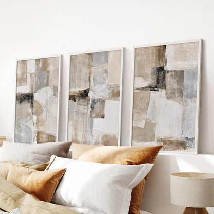 Textured beige abstracts in a set of three framed artworks bring quiet texture over the bed, their white frames suiting a serene bedroom scheme.