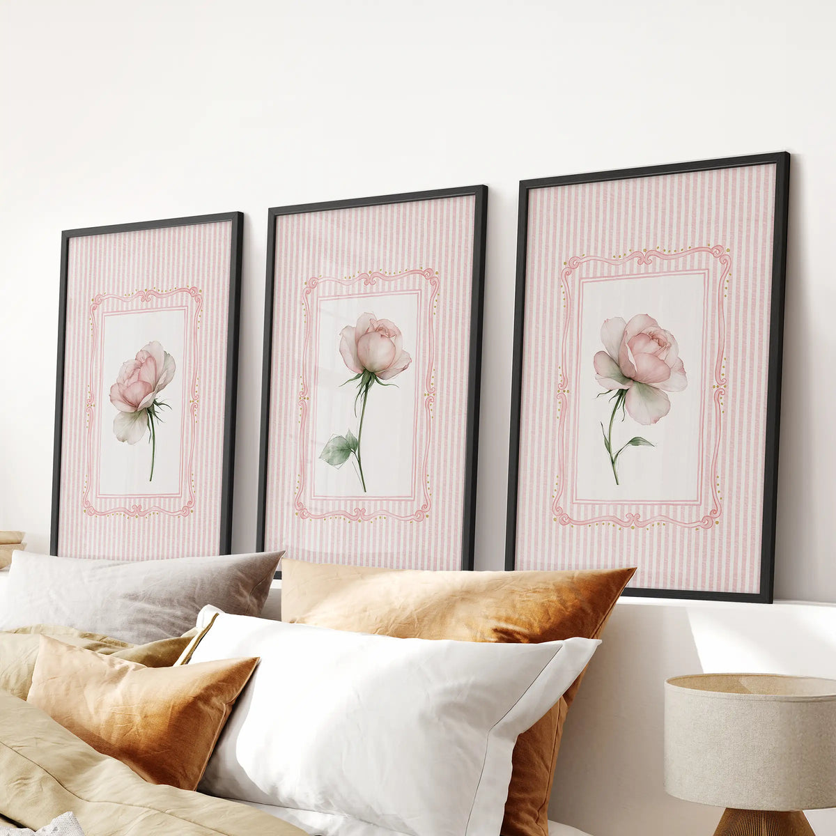 Three-piece rose botanical wall art set in black frames, hanging over the bed in a bedroom.