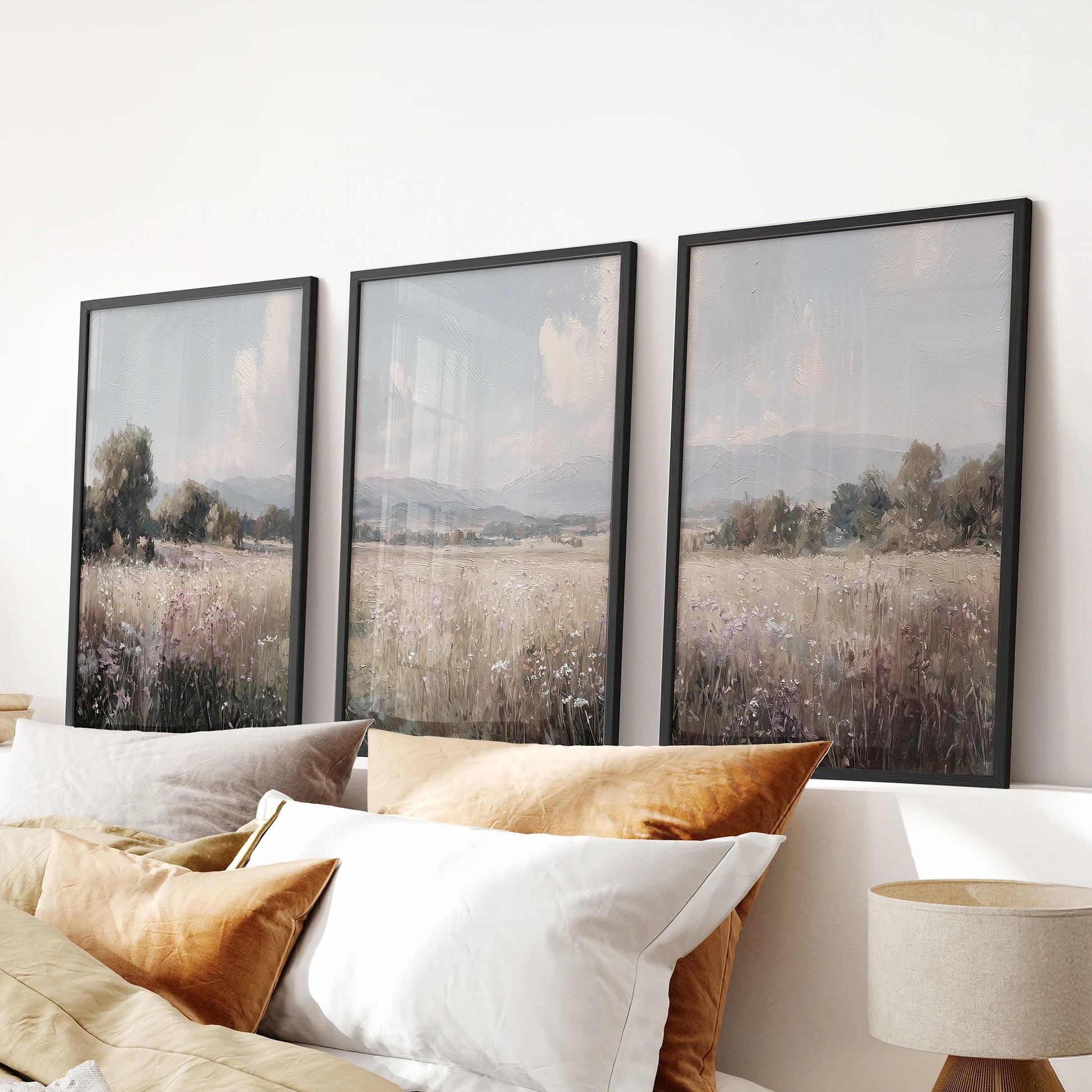 Black framed 3-piece landscape wall decor shows rolling hills and fields, arranged above a bedroom bed headboard for a calm, cohesive look.
