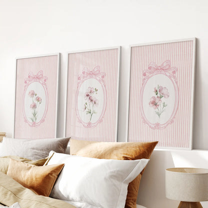 Cottagecore floral prints in a set of three wall decor pieces, white framed over the headboard in a bedroom.