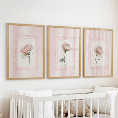 Pink rose wall art, a set of three prints in wood frames, hangs above the cot in a baby nursery.