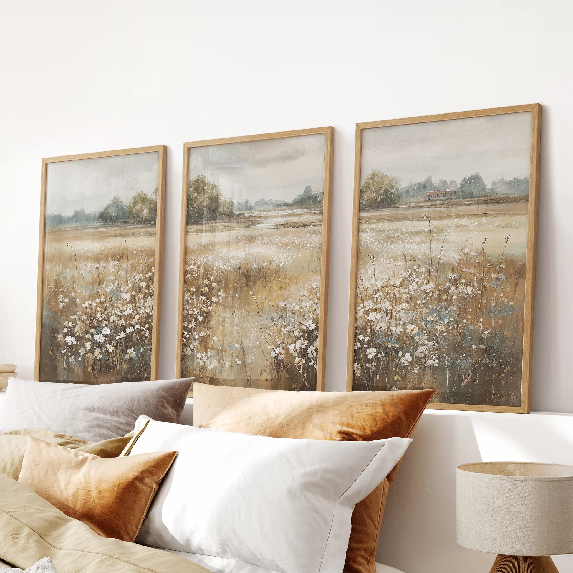 Farmhouse landscapes wall art, a gallery set of three in natural wood frames, layers gentle countryside color above the bed in the bedroom.
