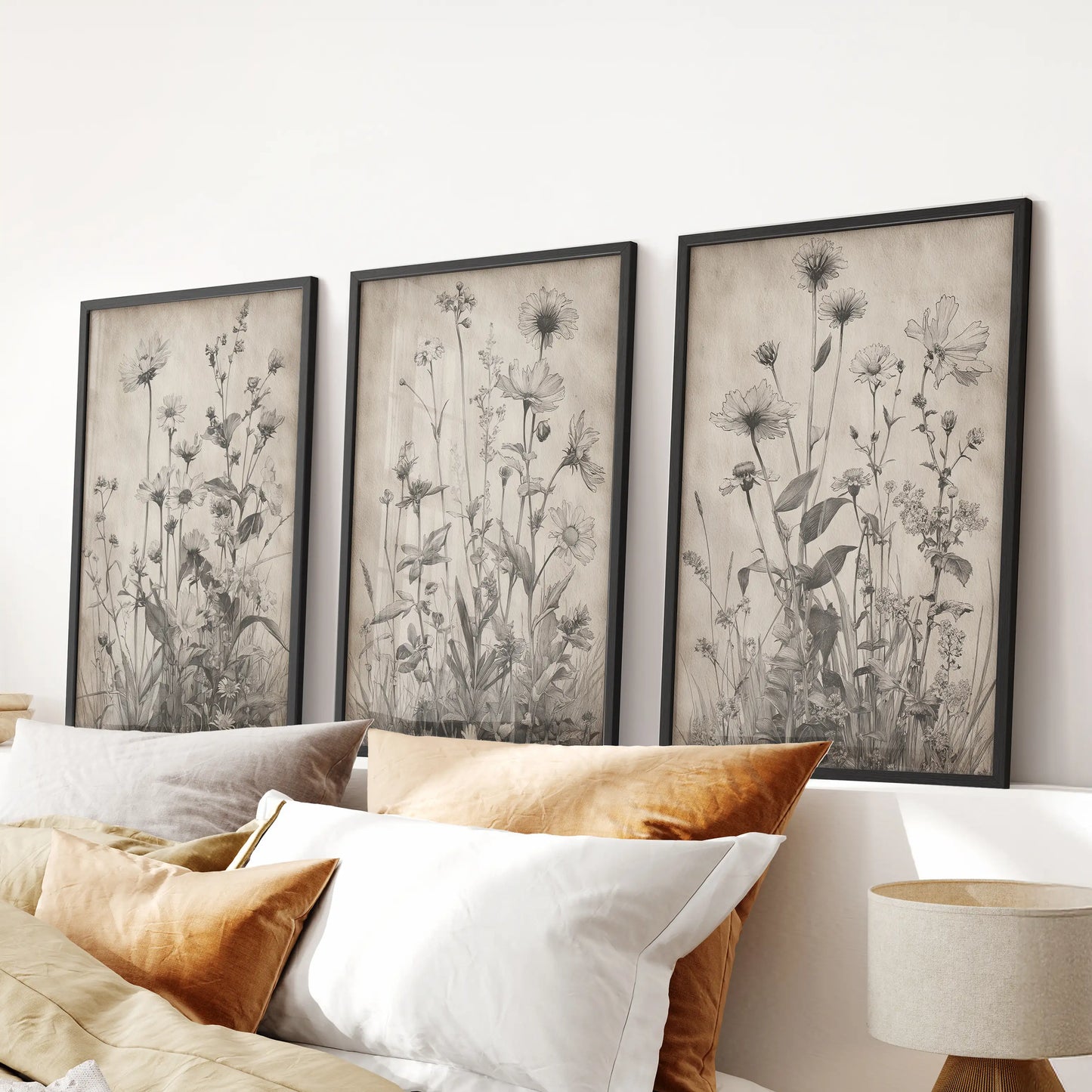 Three wildflower drawings in slim black frames form a calm wall art grouping for the bedroom, centered neatly over the bed.