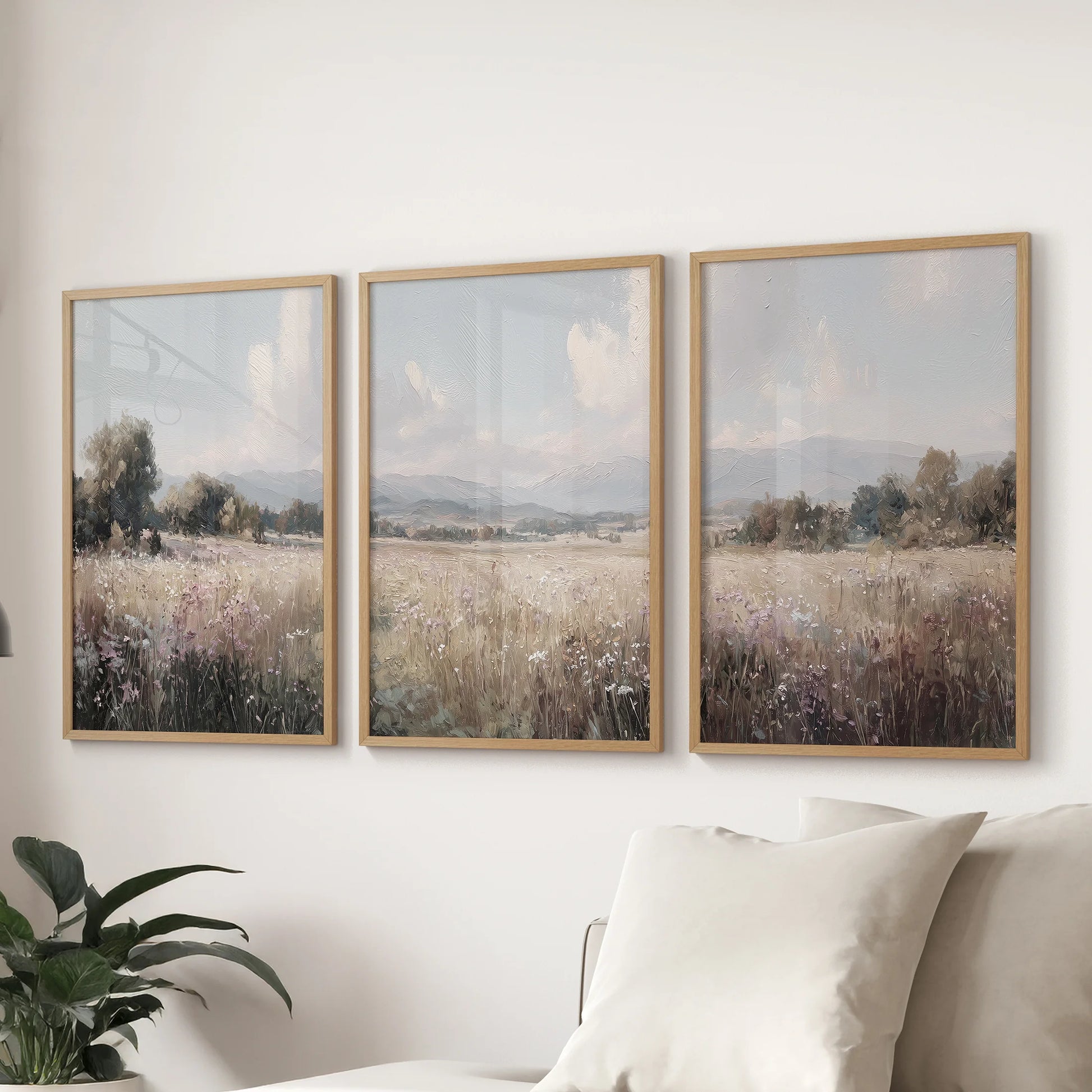 Neutral country landscape art set of 3 in thin wood frames anchors the living room wall over a sectional sofa with soft rustic warmth.