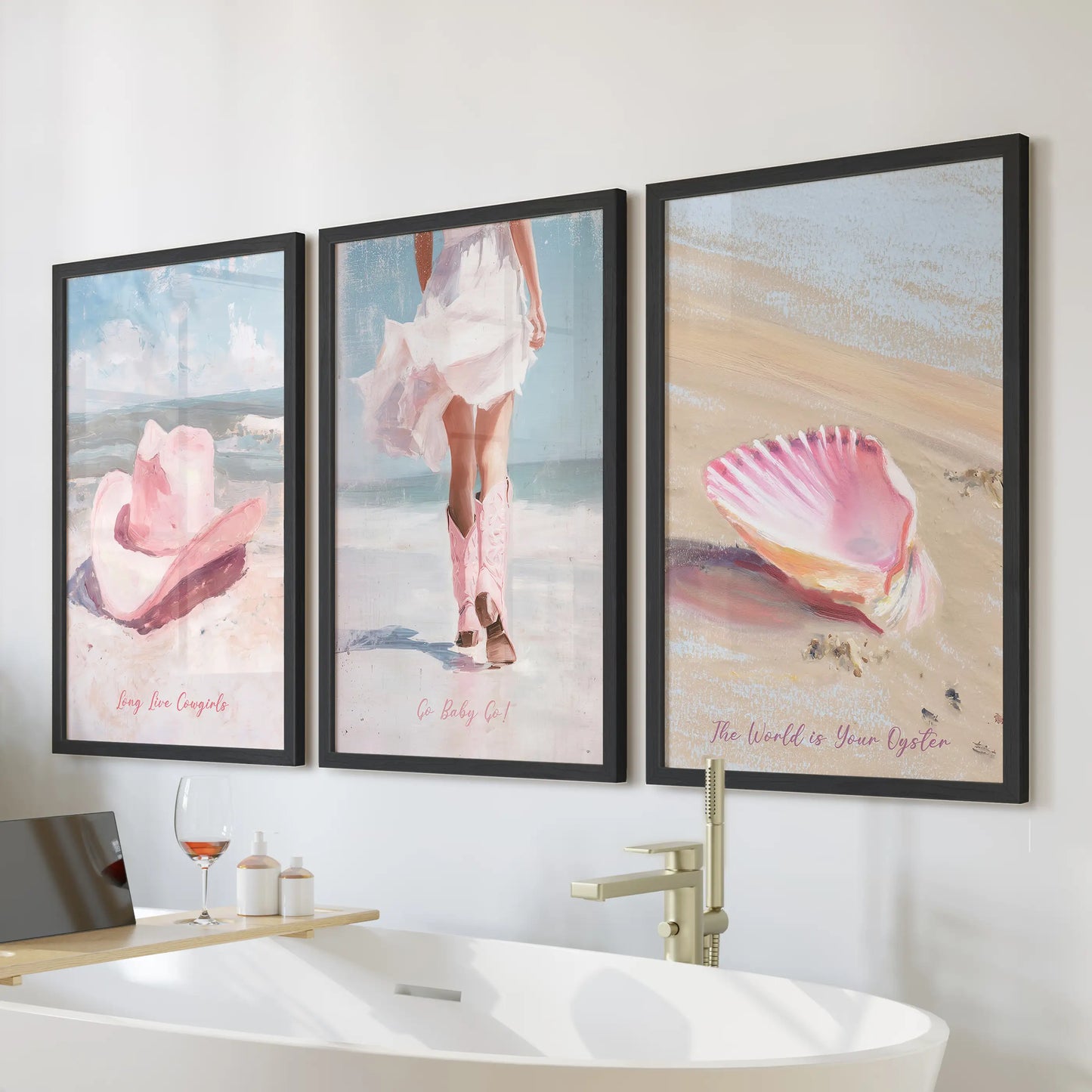 A three-piece wall art set featuring cowgirl hat and boots in black frames hangs above a bathtub, mixing coastal pink warmth with western charm.