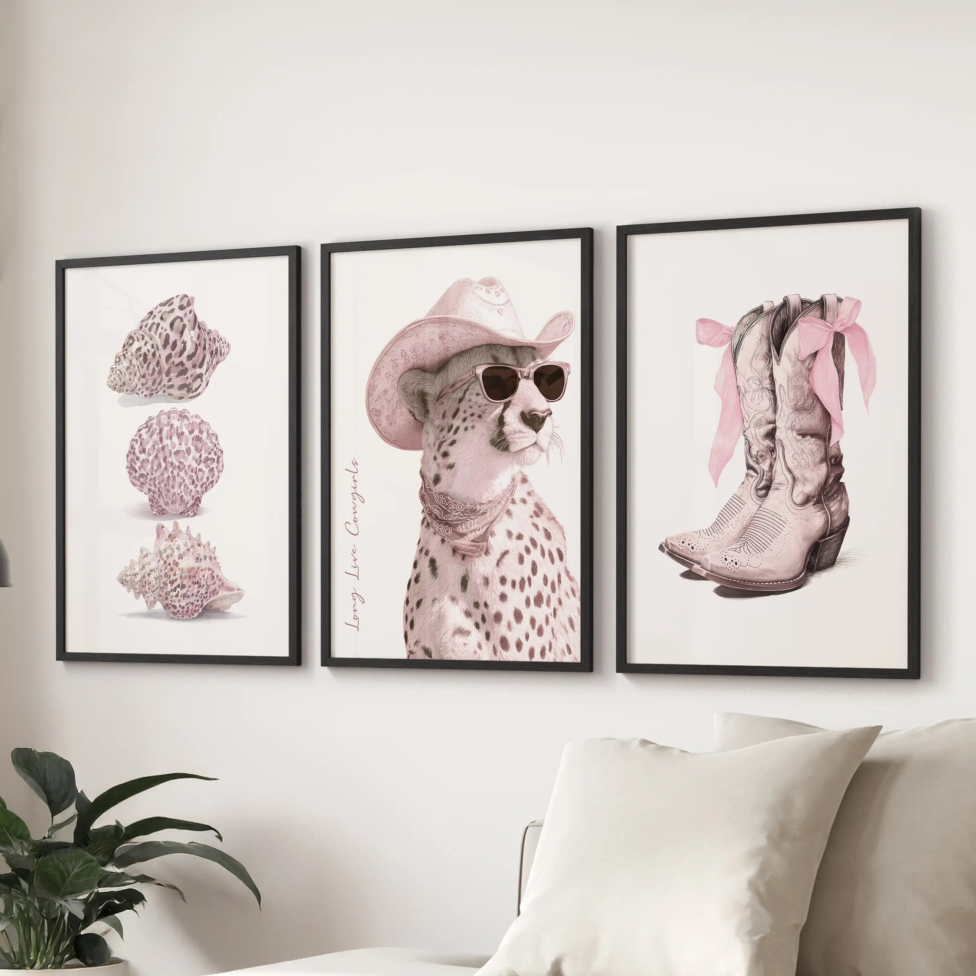 Three black-framed posters with bold lettering and pink details hang above a lounge sectional, celebrating cowgirl spirit with graphic charm.