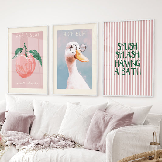 Funny bathroom wall art set of 3 – duck with glasses, peach print, splash bath quote. White frames above the sofa.