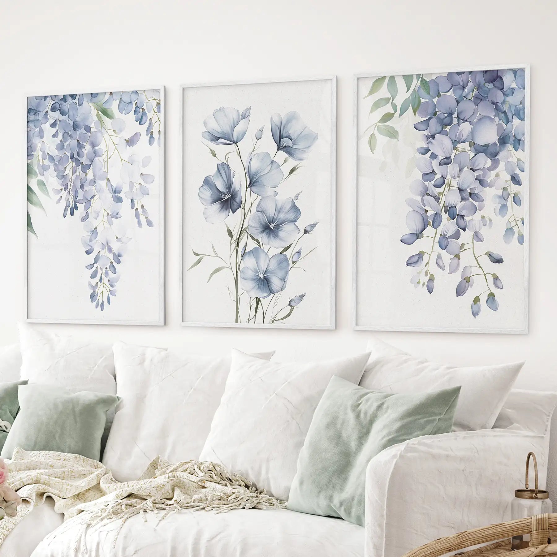 Cottagecore floral artwork. Watercolor set of 3 piece soft blue flower wall decor. White frames above the sofa.