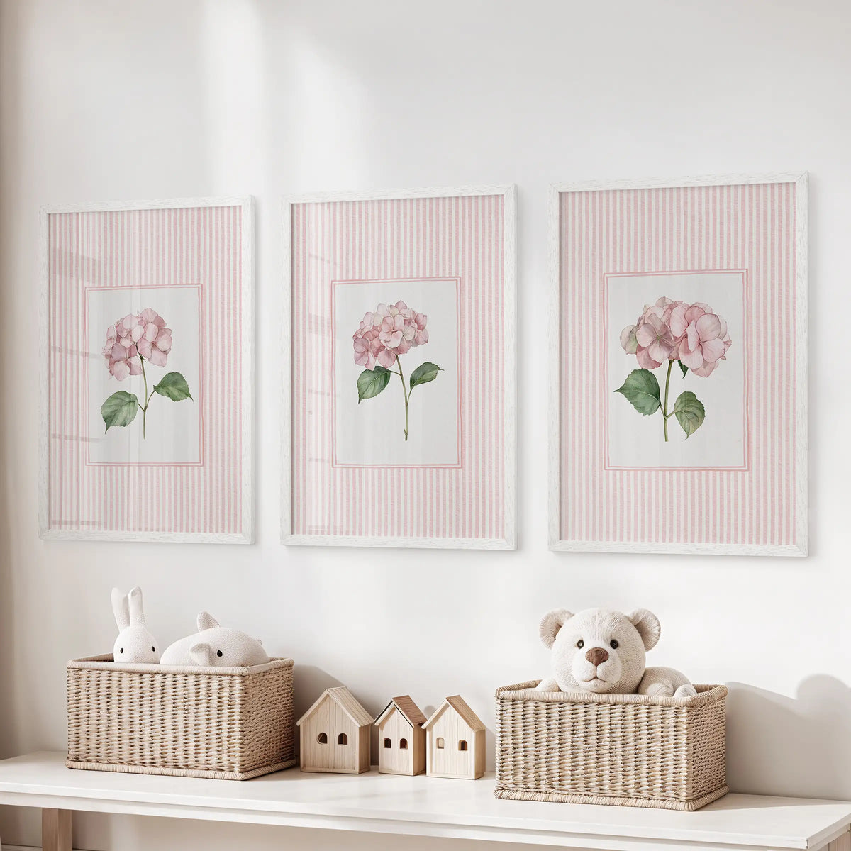 Set of three wall artworks featuring pink striped florals in white frames above a toy organizer in a children's playroom.