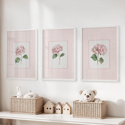 Set of three wall artworks featuring pink striped florals in white frames above a toy organizer in a children's playroom.