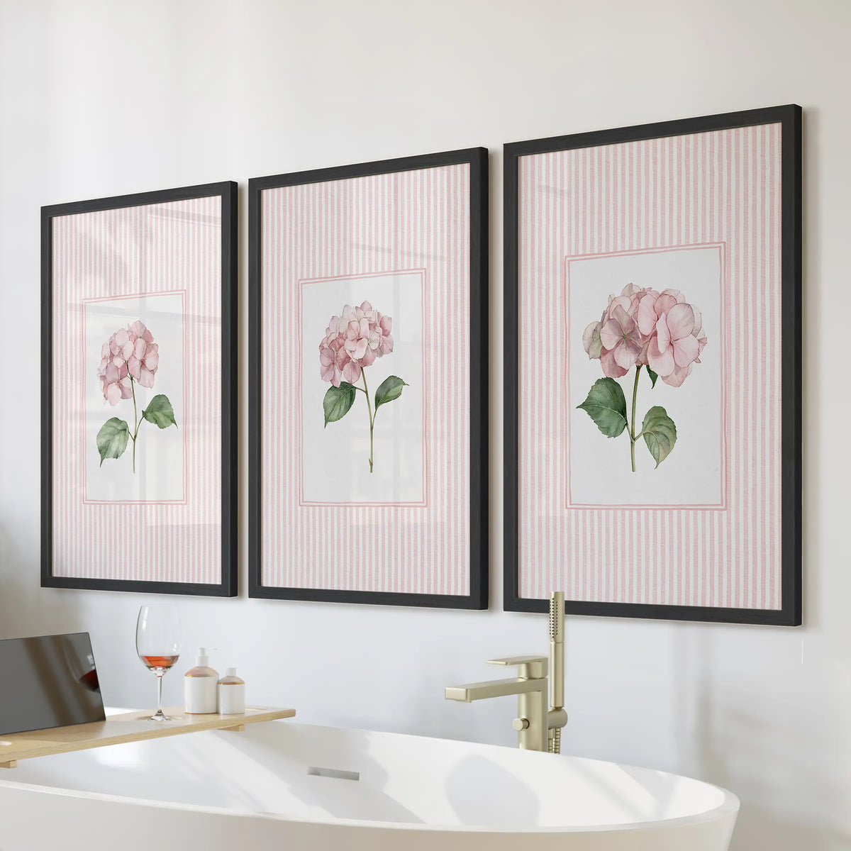Pink striped florals in a three-piece wall decor set are displayed in black frames above a freestanding tub in a bathroom.