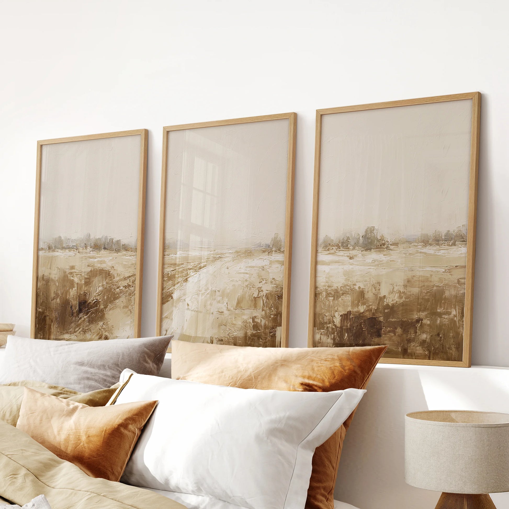 Three wall art prints of minimalist farmhouse landscapes in natural wood frames ground the bedroom when hung just over the headboard.