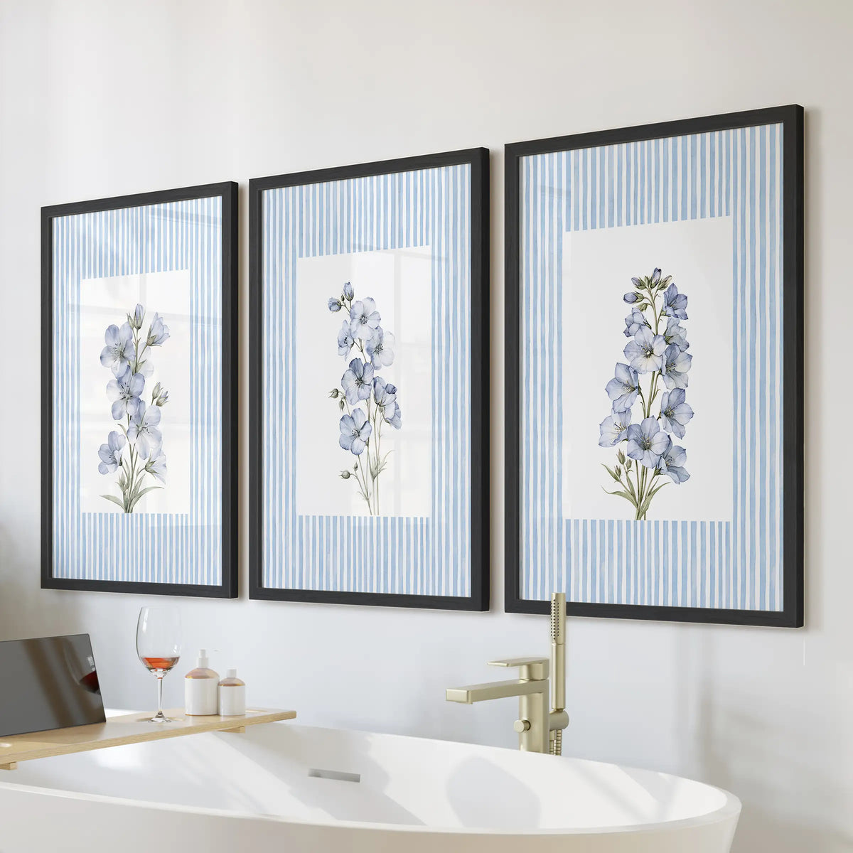 Three-piece blue floral watercolor wall art in black frames, displayed over a freestanding tub in a bathroom.