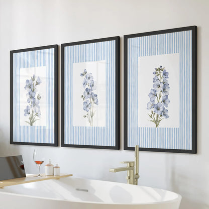 Three-piece blue floral watercolor wall art in black frames, displayed over a freestanding tub in a bathroom.